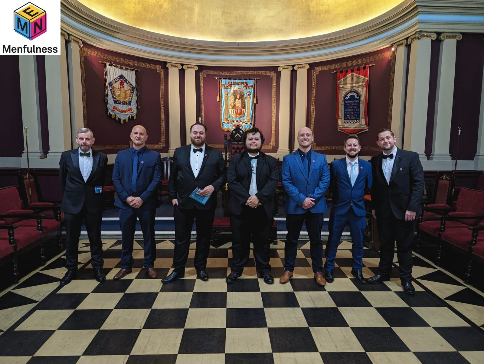 a line of smiling people stood in a masonic temple