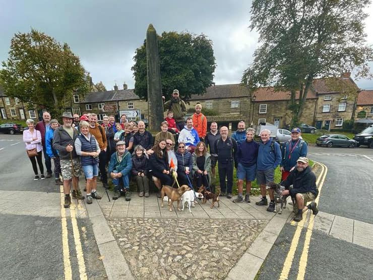 a group of smiling people stood in front of a monument